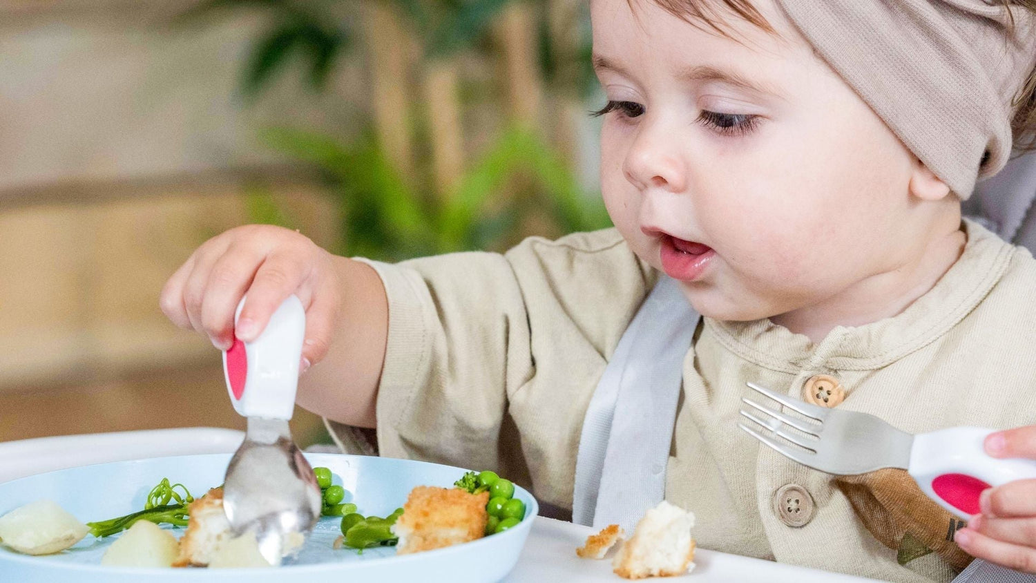 toddler girl happily uses doddl toddler spoon and fork to eat a nutritious meal