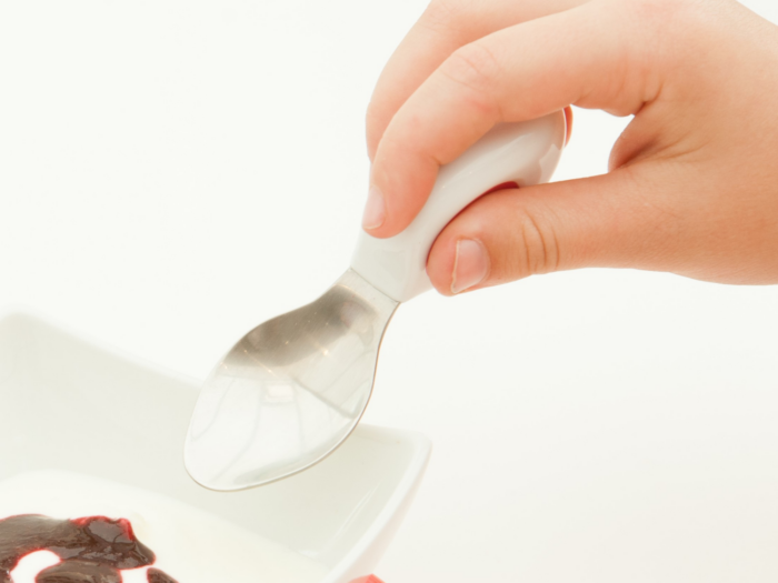 Little hand showing doddl spoon and using pincer grasp|Bio image of Christine Pollack OTR/L|Child being helped by adult to cut food using a doddl knife|Little hand showing doddl spoon and using pincer grasp