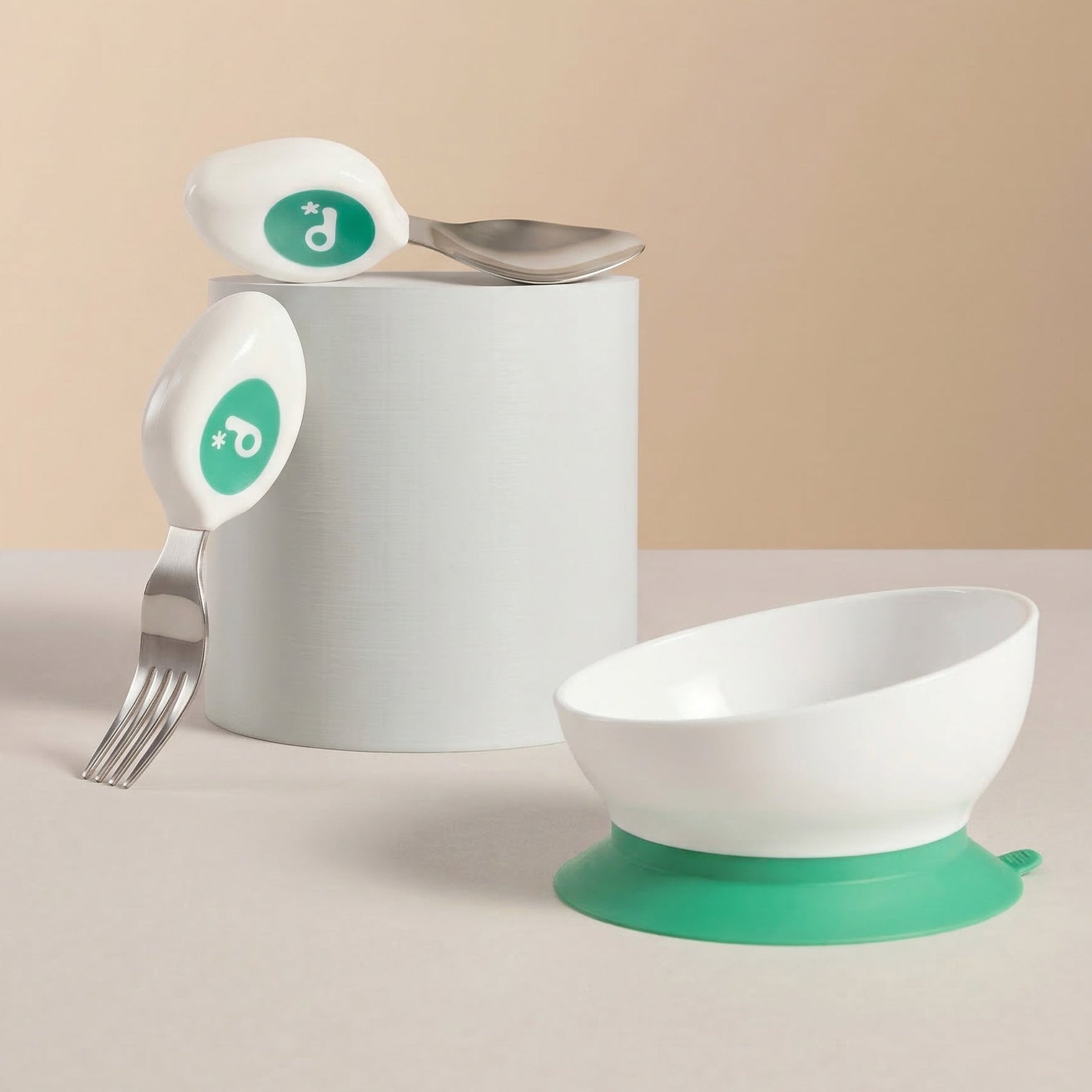 Children's tableware set with bowl, spoon, and fork on a beige background